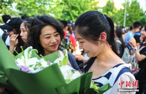 資料圖：山東濟(jì)南眾多考生手捧鮮花在家長(zhǎng)的簇?fù)硐職g快告別高考。中新社記者 張勇 攝