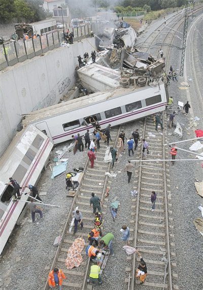 24日，救援人員在西班牙列車脫軌現(xiàn)場(chǎng)。一節(jié)車廂被強(qiáng)大的慣性拋上鐵道邊的高臺(tái)。