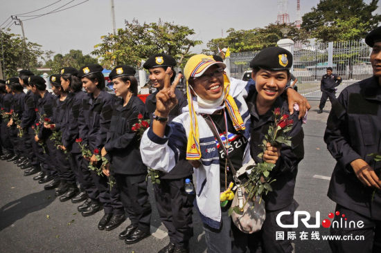 2013年12月03日,曼谷總理府與曼谷警署允許反政府示威民眾進入,雙方進入暫時“停戰(zhàn)”狀態(tài)迎接泰王生日。曼谷警察總署,女警們手持鮮花送給反政府示威民眾。圖片來源:Manish Swarup/東方IC