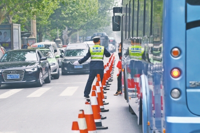 省人民醫(yī)院南門的路中間擺放反光錐，交警示意由西向東車輛從前方繞行。