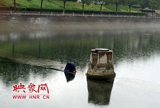 一女子穿著雨披獨(dú)自站在東風(fēng)渠中