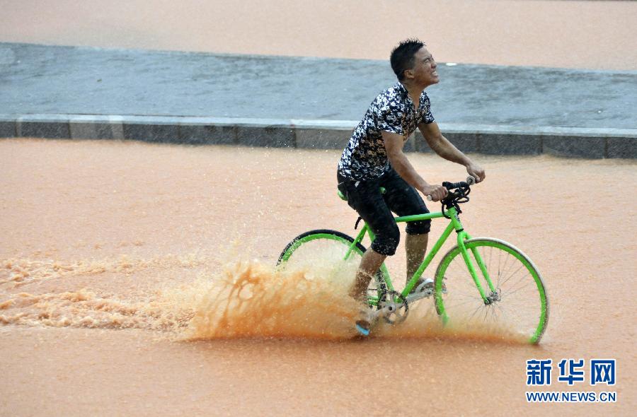 5月11日，一名行人在深圳街頭冒雨騎行。